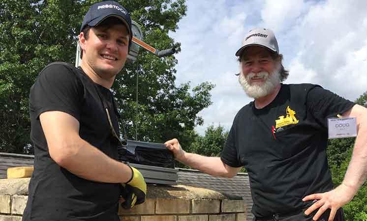 Timothy Weaver and founder Doug Ault shaking hands atop a chimney