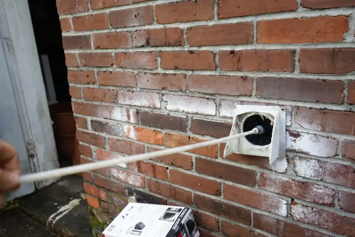 Abbey Road technician brushing lint from a dryer-vent outlet in Memphis